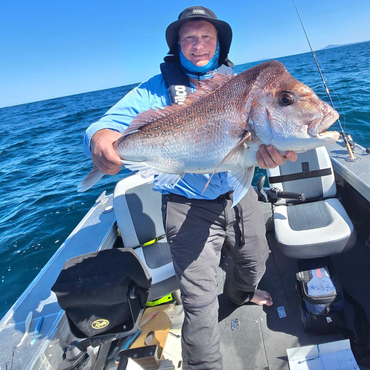 Man holding a large fish on a boat in the ocean